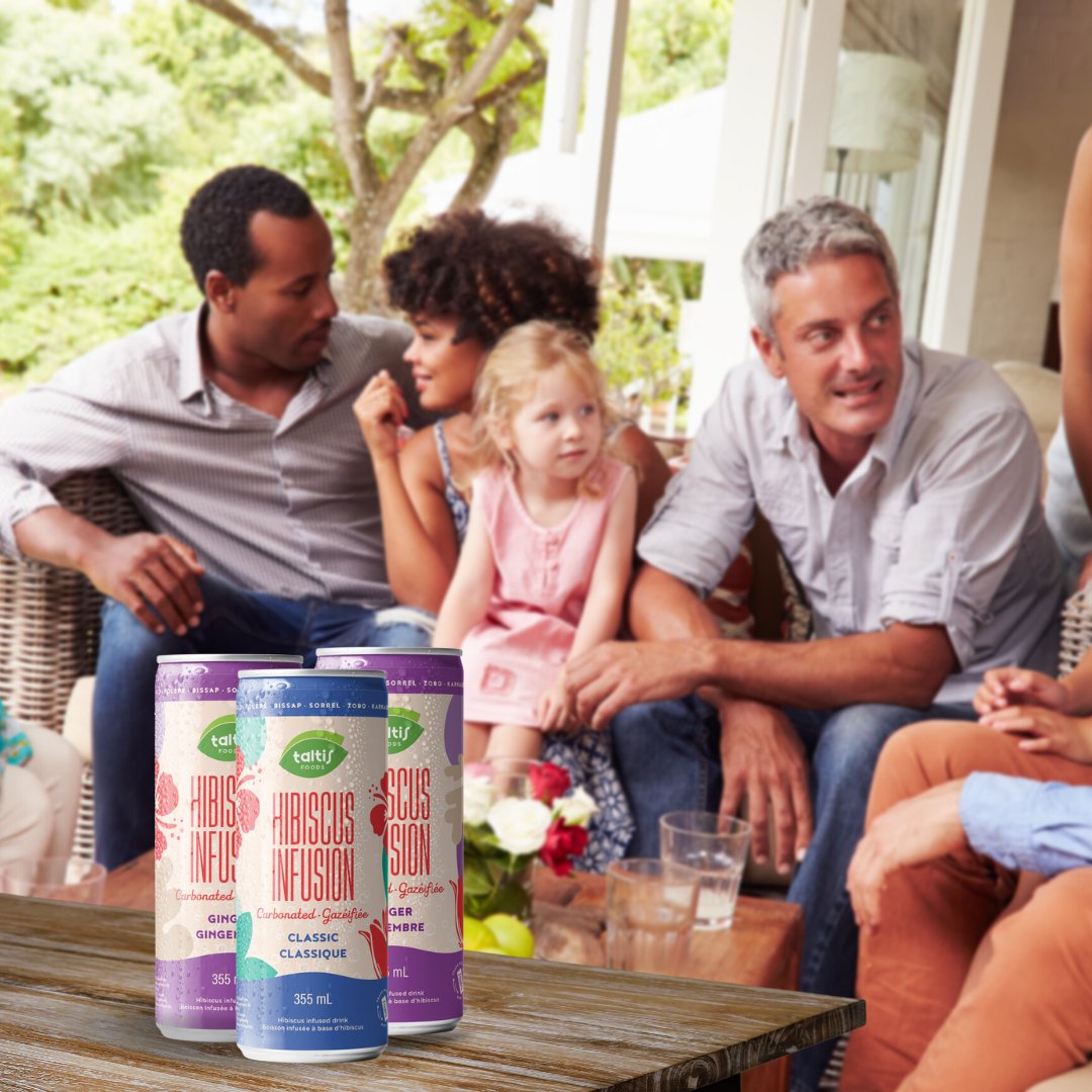 Family enjoying a casual outdoor gathering with Taltis Foods Hibiscus Infusion carbonated drinks on display, 355 mL cans with refreshing hibiscus design, promoting a relaxed lifestyle.